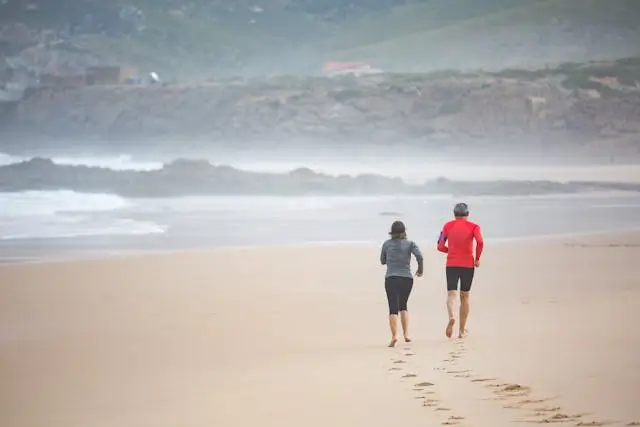Middle-aged couple jogging on the beach, symbolizing energy and vitality from BHRT in Searcy, AR